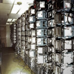 Rows of industrial machines and wiring in a large facility.