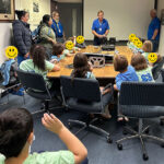 Children seated around table watching instructor demonstration